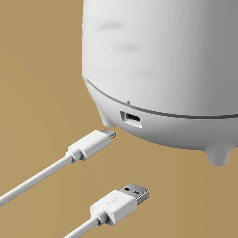 White volcano-shaped ultrasonic humidifier with USB cable on desk in a room