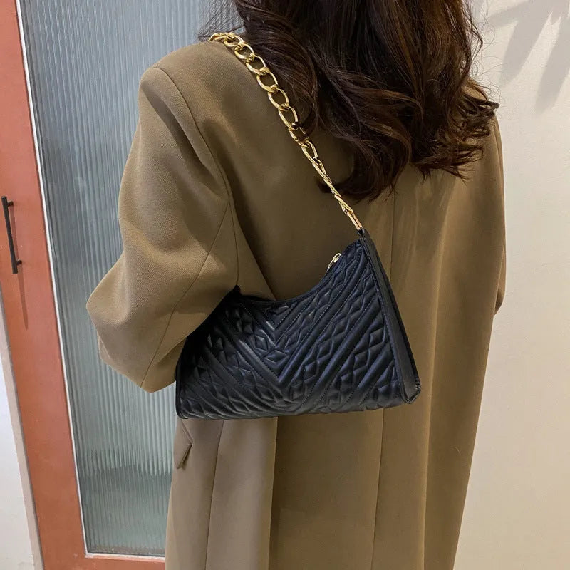 Black pleated chain baguette shoulder bag with adjustable strap and soft handle on white background