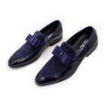 Men's black patent leather dress shoes with a gold tassel detail on the front.