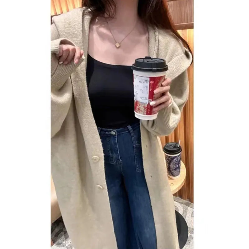 Woman wearing a long, loose, hooded knitted cardigan in a neutral colour, Korean casual style.