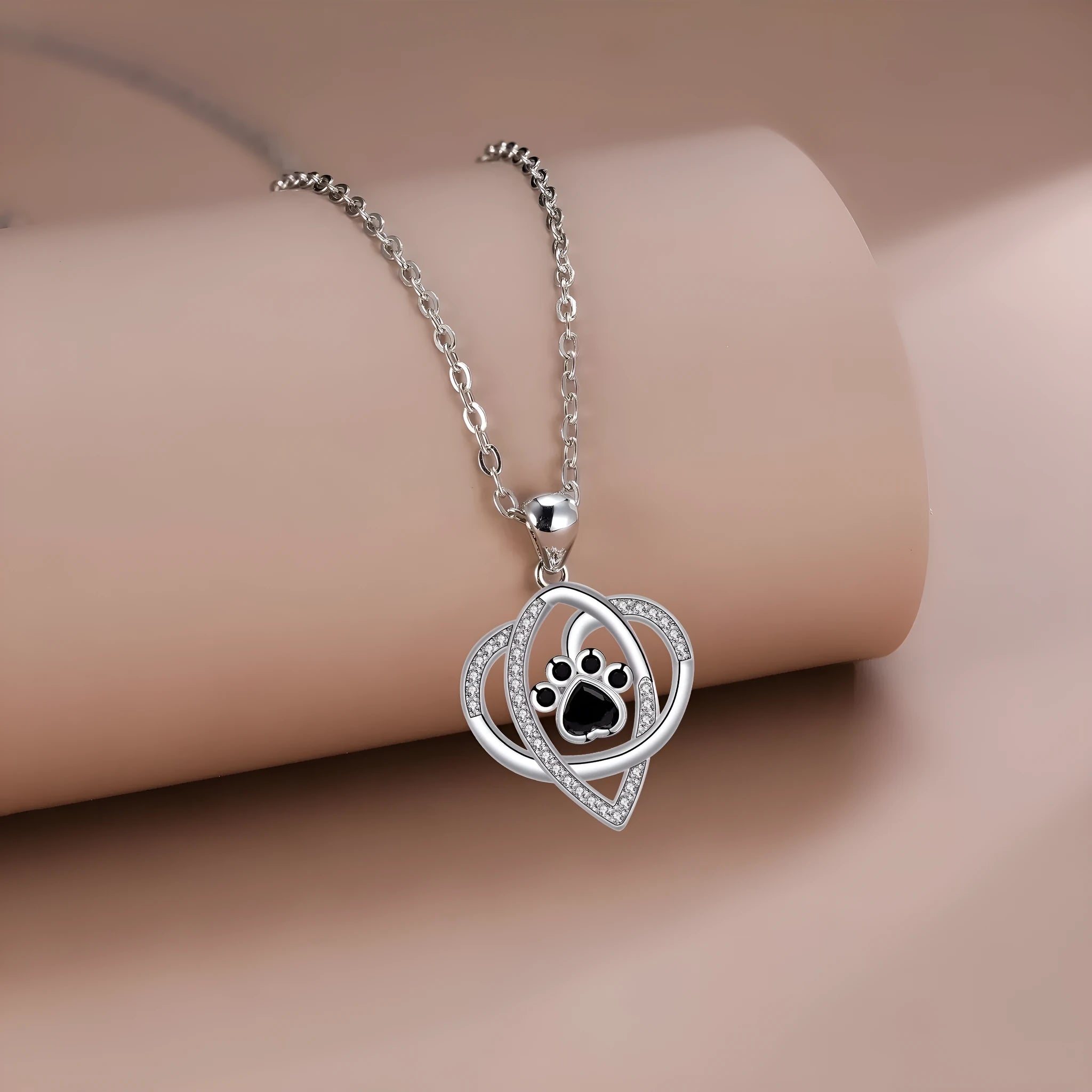 Close-up of electroplated copper paw print necklace pendant on adjustable cross chain