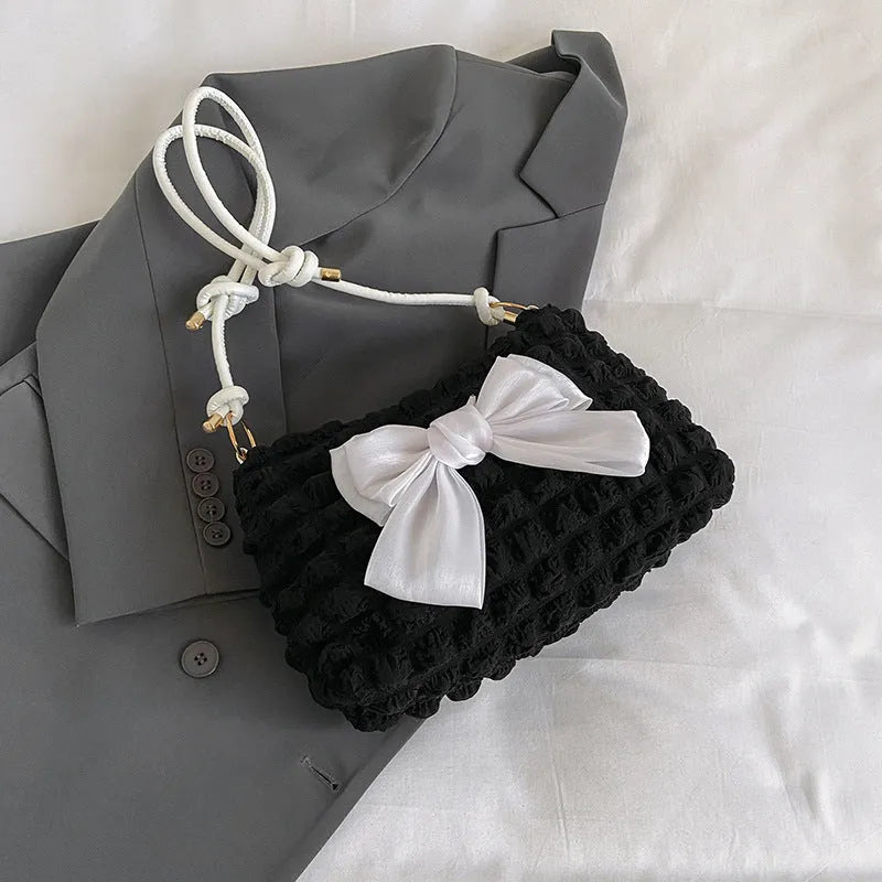 Black canvas horizontal square women's handbag with a single shoulder strap and an outer sandwich pocket.