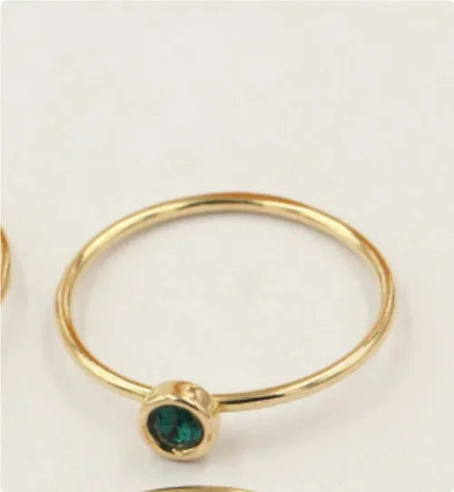 Gold-plated women's knuckle ring with clear stones in green, blue, red, or white on a copper band.