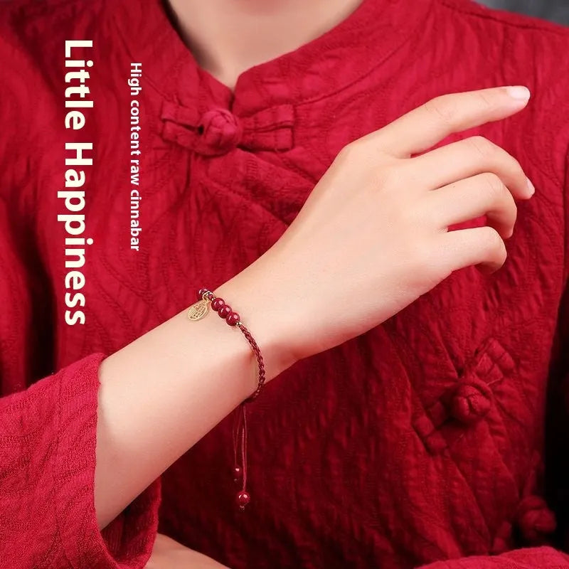 Cinnabar round bead blessing card bracelet with adjustable braided rope on neutral background