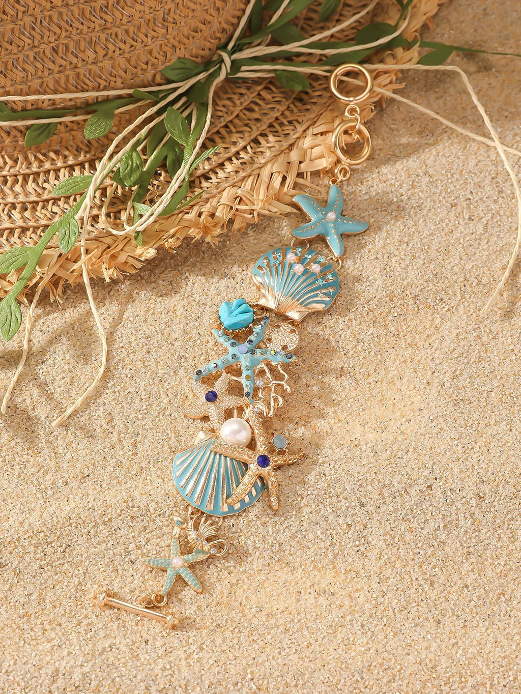 Alloy starfish bracelet with blue coral rhinestone boat anchor charm on a wrist.