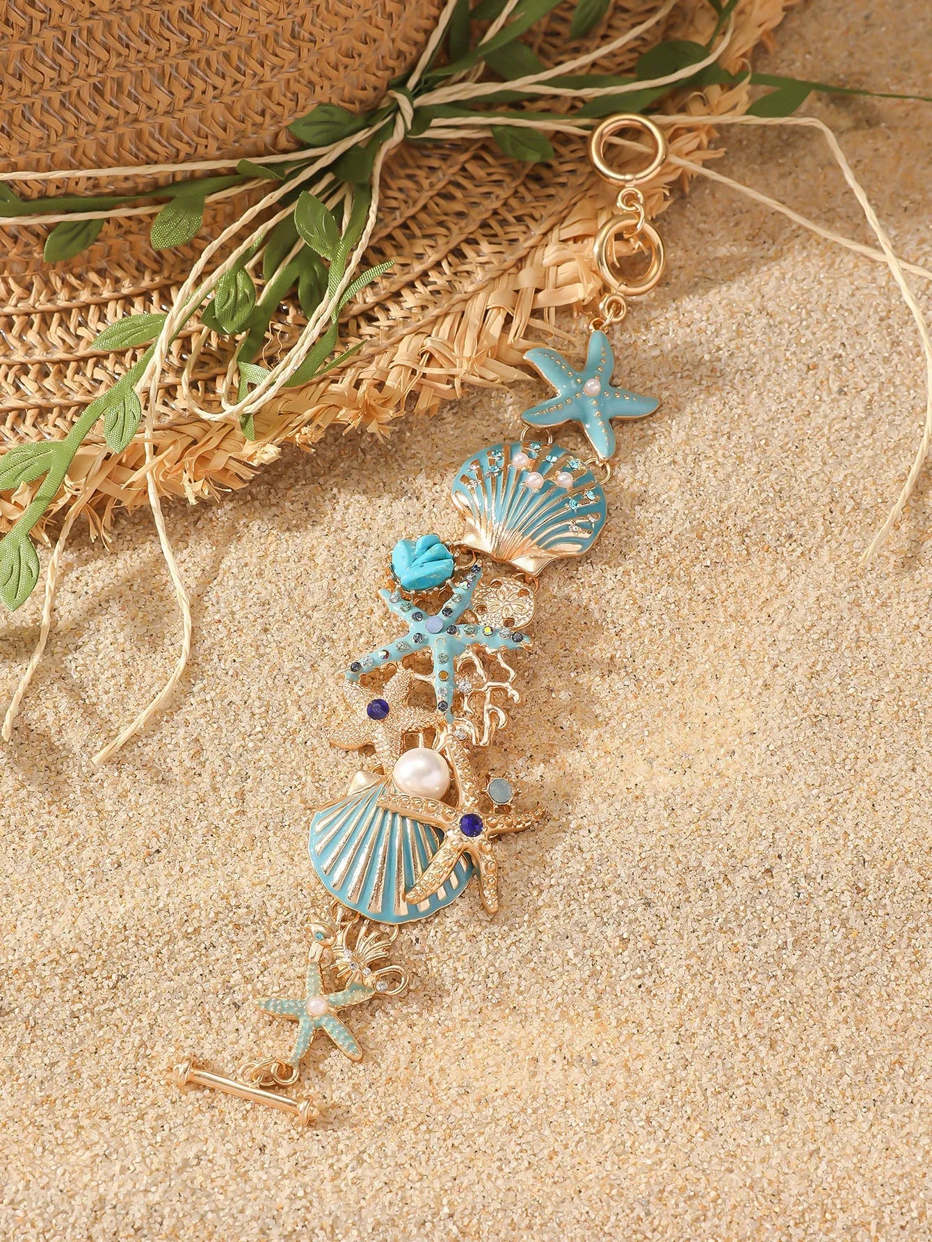 Alloy starfish bracelet with blue coral rhinestone boat anchor charm on a wrist.