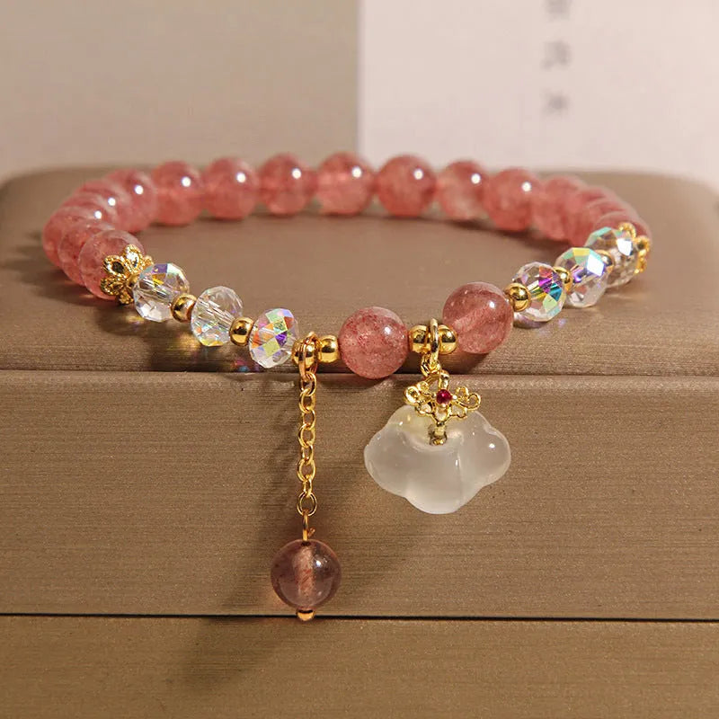 Women's natural strawberry quartz and white agate crystal bracelet with auspicious cloud pattern on a flat surface