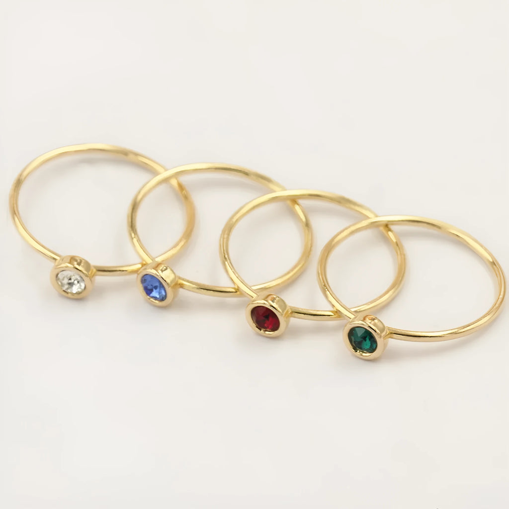 Gold-plated women's knuckle ring with clear stones in green, blue, red, or white on a copper band.