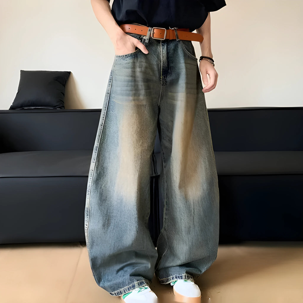 Man wearing retro blue distressed denim wide-leg trousers with a slim fit and zipper fly