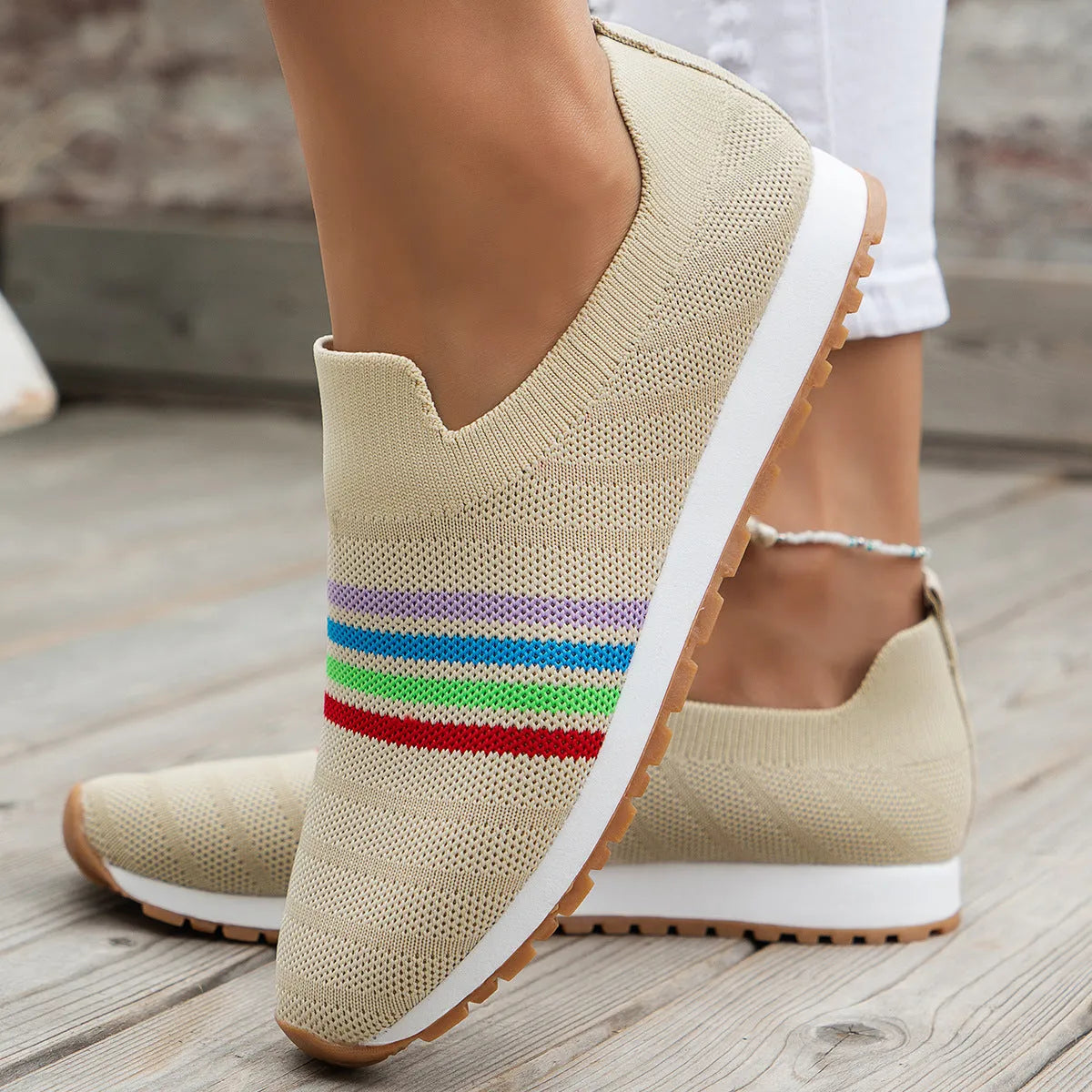 Women's casual flat sneaker pumps in beige with low wedge heel and round toe, side view on wooden floor