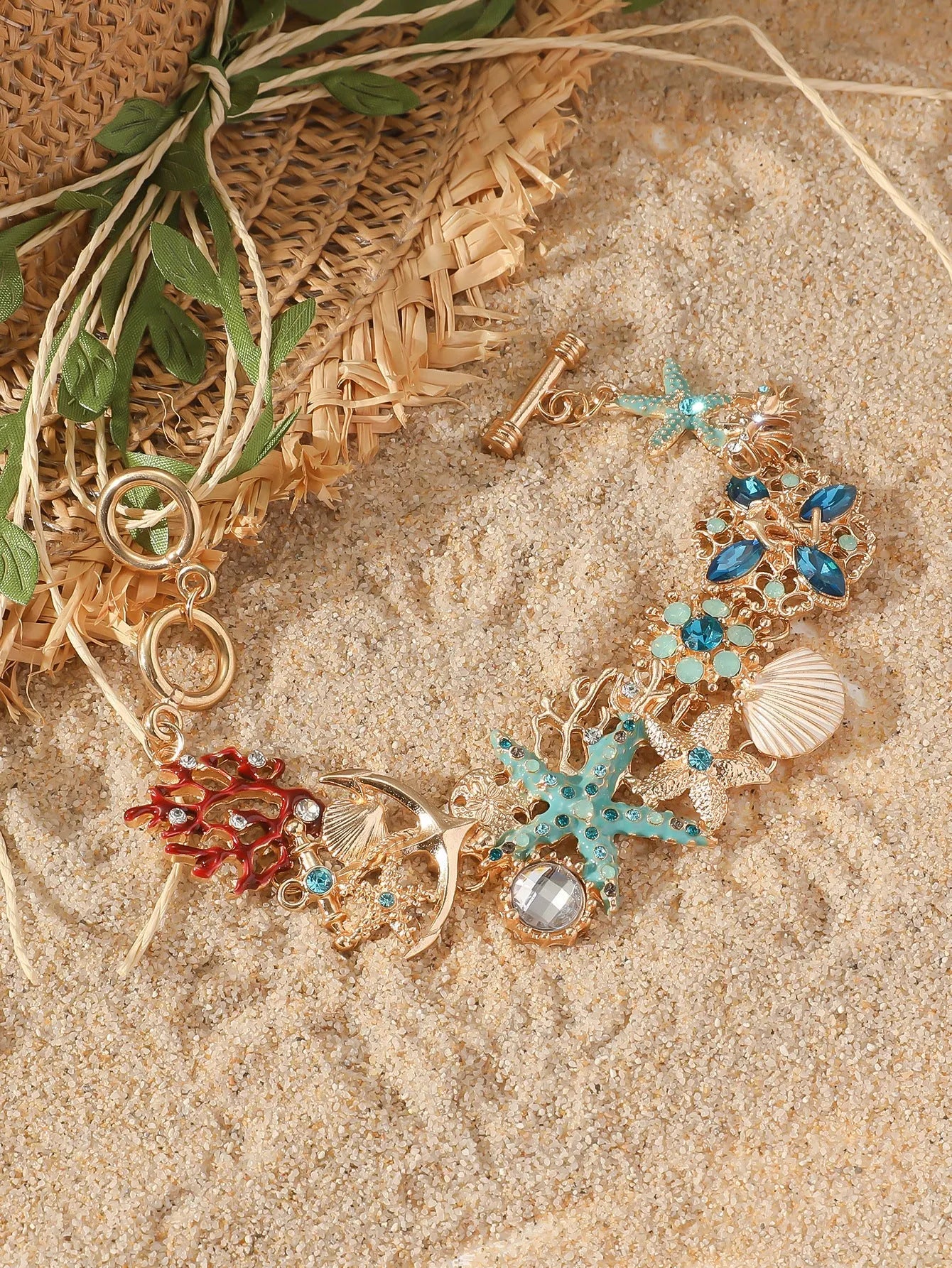 Alloy starfish bracelet with blue coral rhinestone boat anchor charm on a wrist.