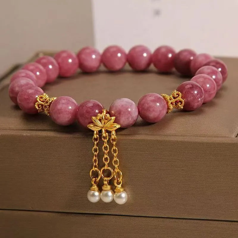 Natural stone beaded bracelet with pink lotus tassel, pearl pendant, and electroplated crystal beads on white background