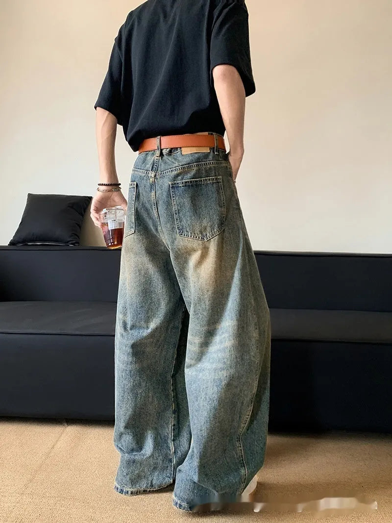 Man wearing retro blue distressed denim wide-leg trousers with a slim fit and zipper fly