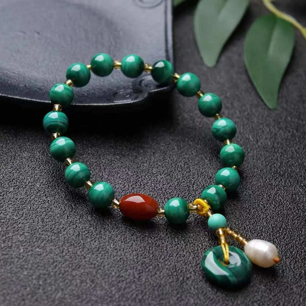 Handmade natural malachite and red agate barrel bead bracelet on a wrist, showing green and red stone details.