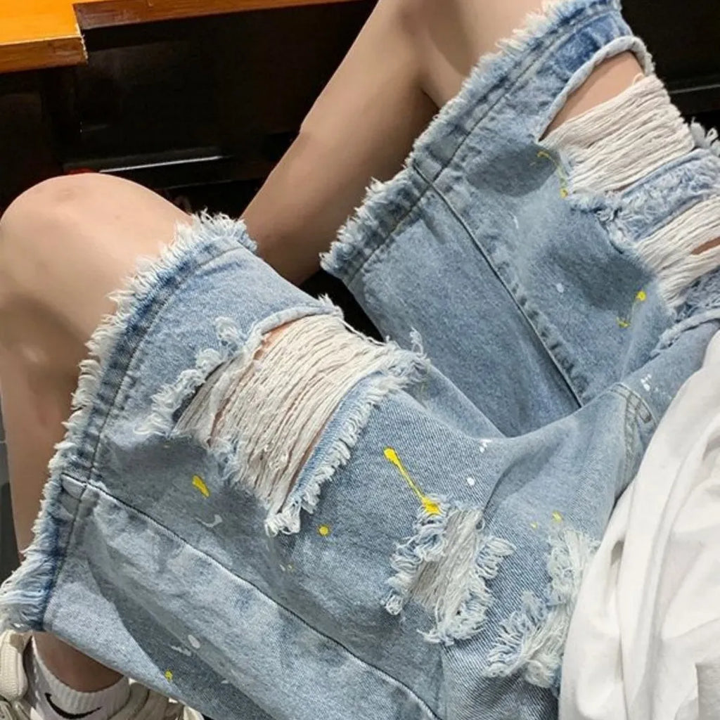 Men's loose fit denim shorts in light blue with water washed hole detail, laid flat.