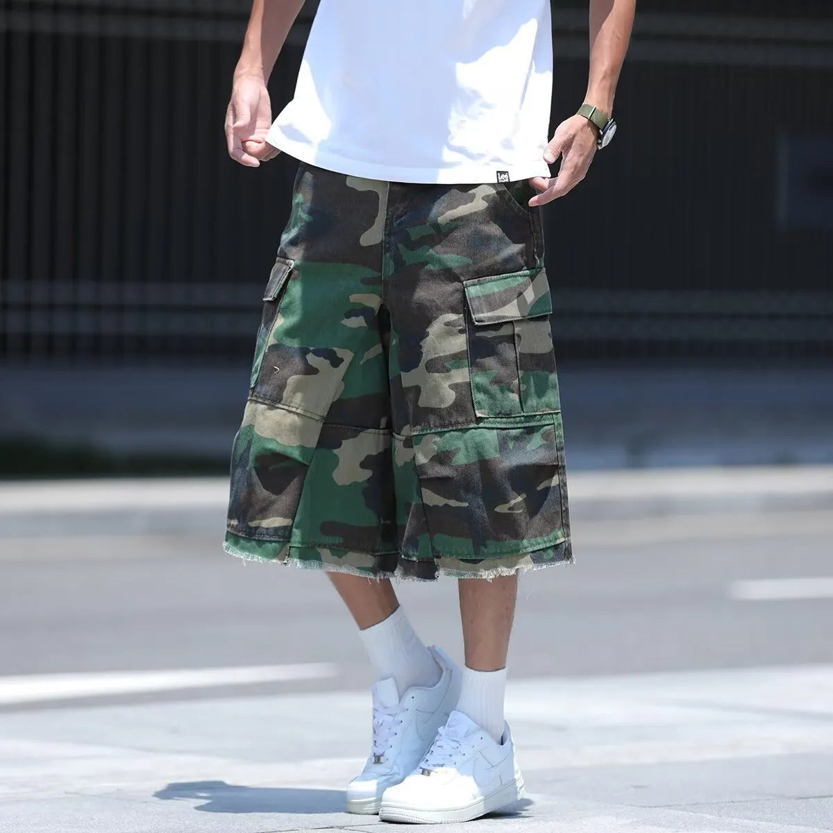 Man wearing loose-fit cropped camouflage shorts in retro American workwear style.