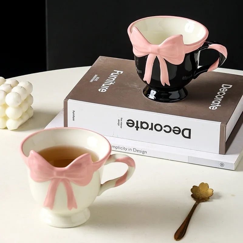 White ceramic mug with a pink heart and black bow design, 350ml capacity.