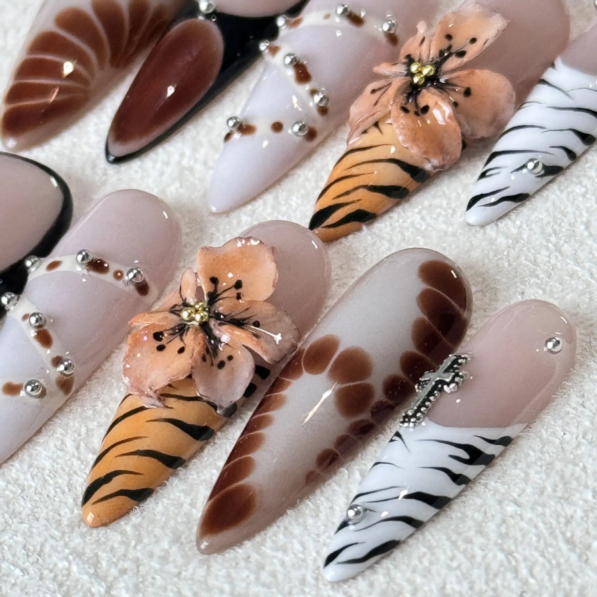 Leopard print false nails with cross and flower designs, shown in long wear armour style