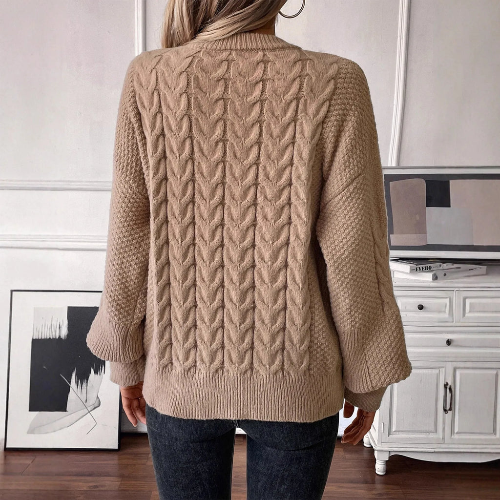 Woman wearing a loose beige round neck sweater with a twisted knit texture detail on the front.