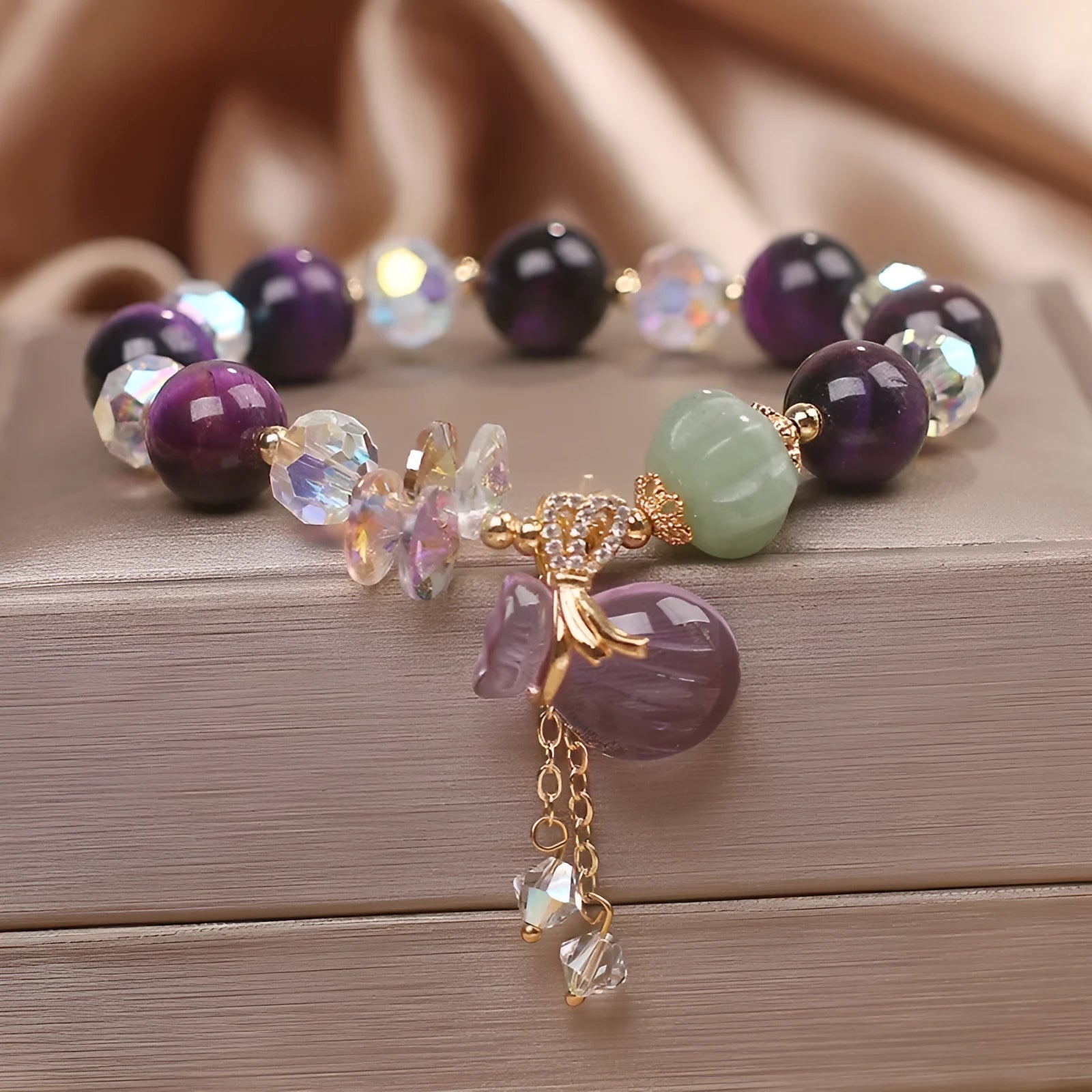 Women's crystal bracelet with purple Tigereye money bag pendant and clear rhinestone accents