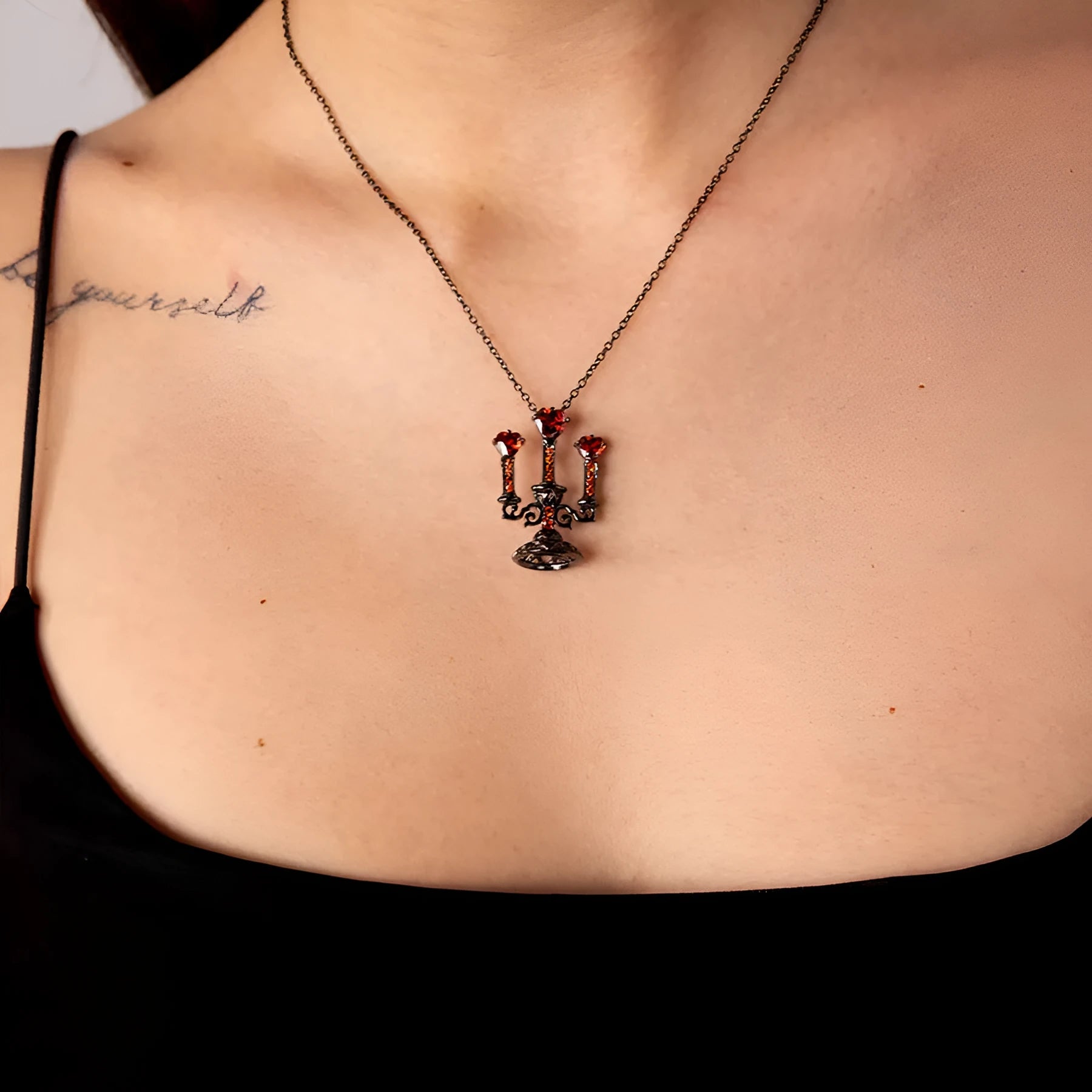 Close-up of a women's Gothic alloy necklace with a hollow candlestick pendant and cross chain links.