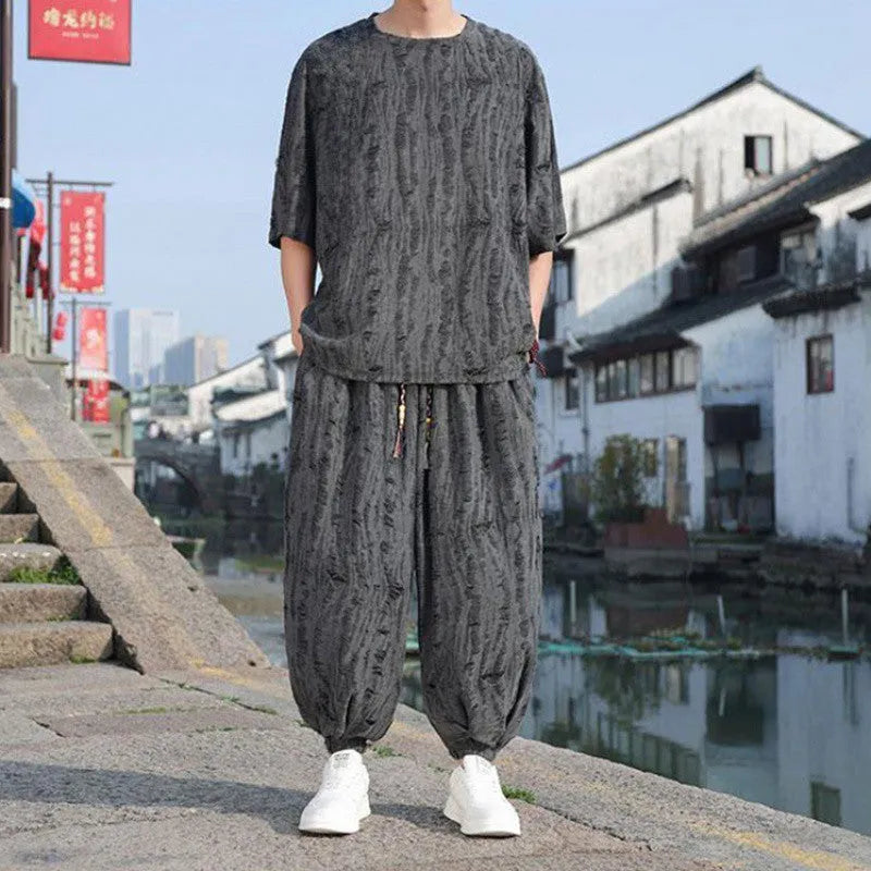 Men's thin short-sleeved loose two-piece knitwear suit in black on model, with cropped trousers