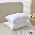 White cotton satin stripe pillow with feather and cotton filling shown in adult bedding setting.