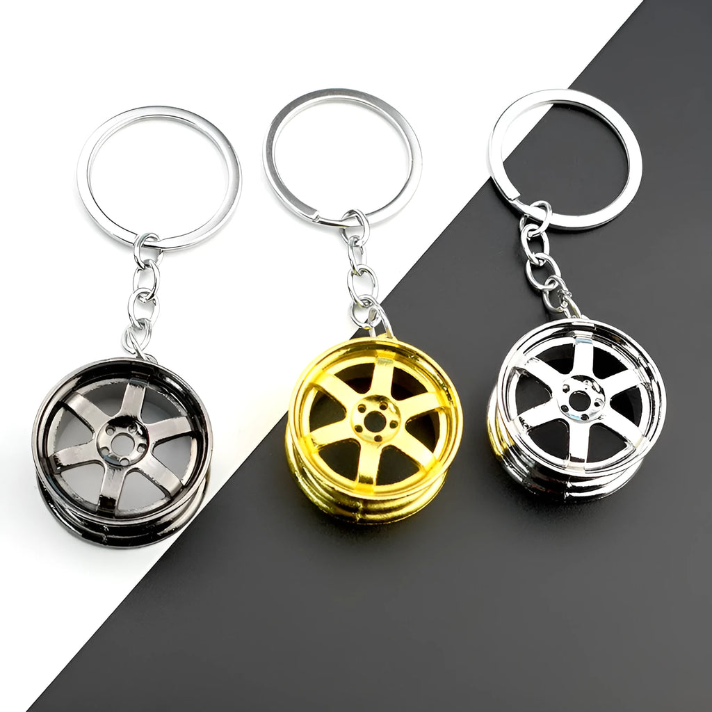 Zinc alloy car wheel hub keychain in gold finish with detailed hub pattern on white background