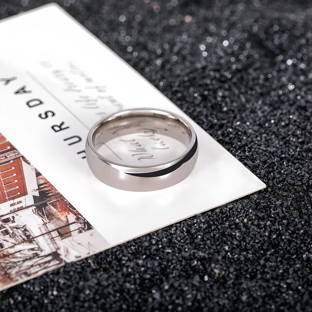 Silver titanium steel unisex ring on a finger, showing minimalist band in 2mm, 4mm, and 6mm width options.