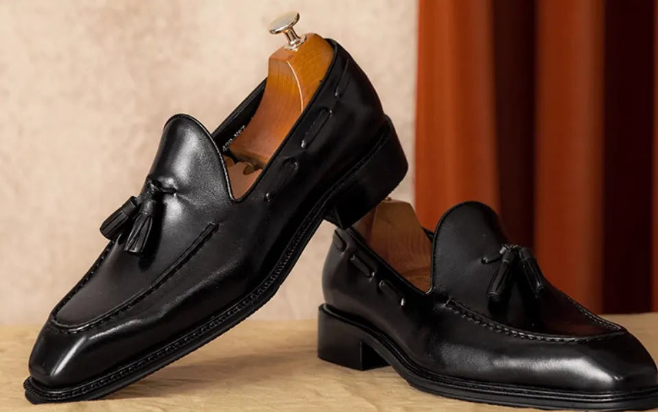 Men's black leather slip-on loafers with fringed detail and rubber sole