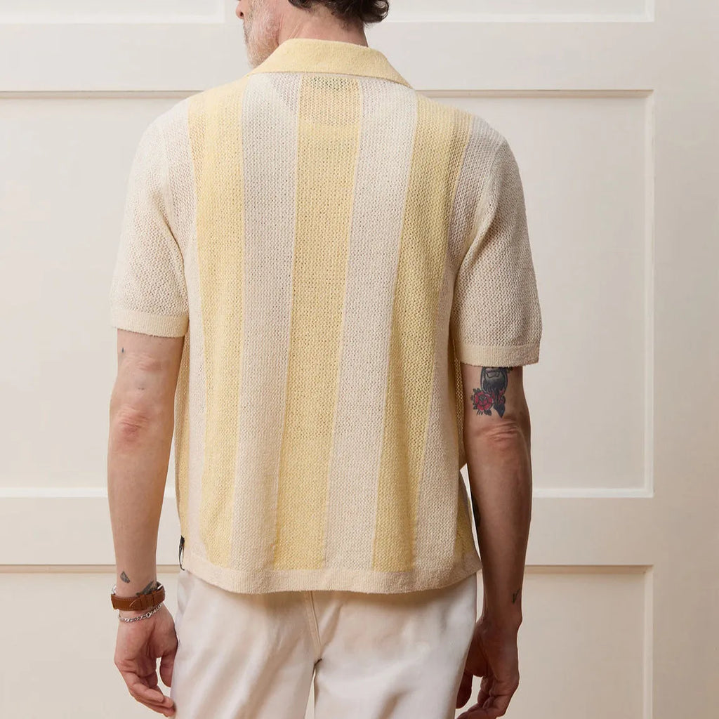 Yellow women's short-sleeved polo shirt with hollow-out asymmetric detail on a hanger.