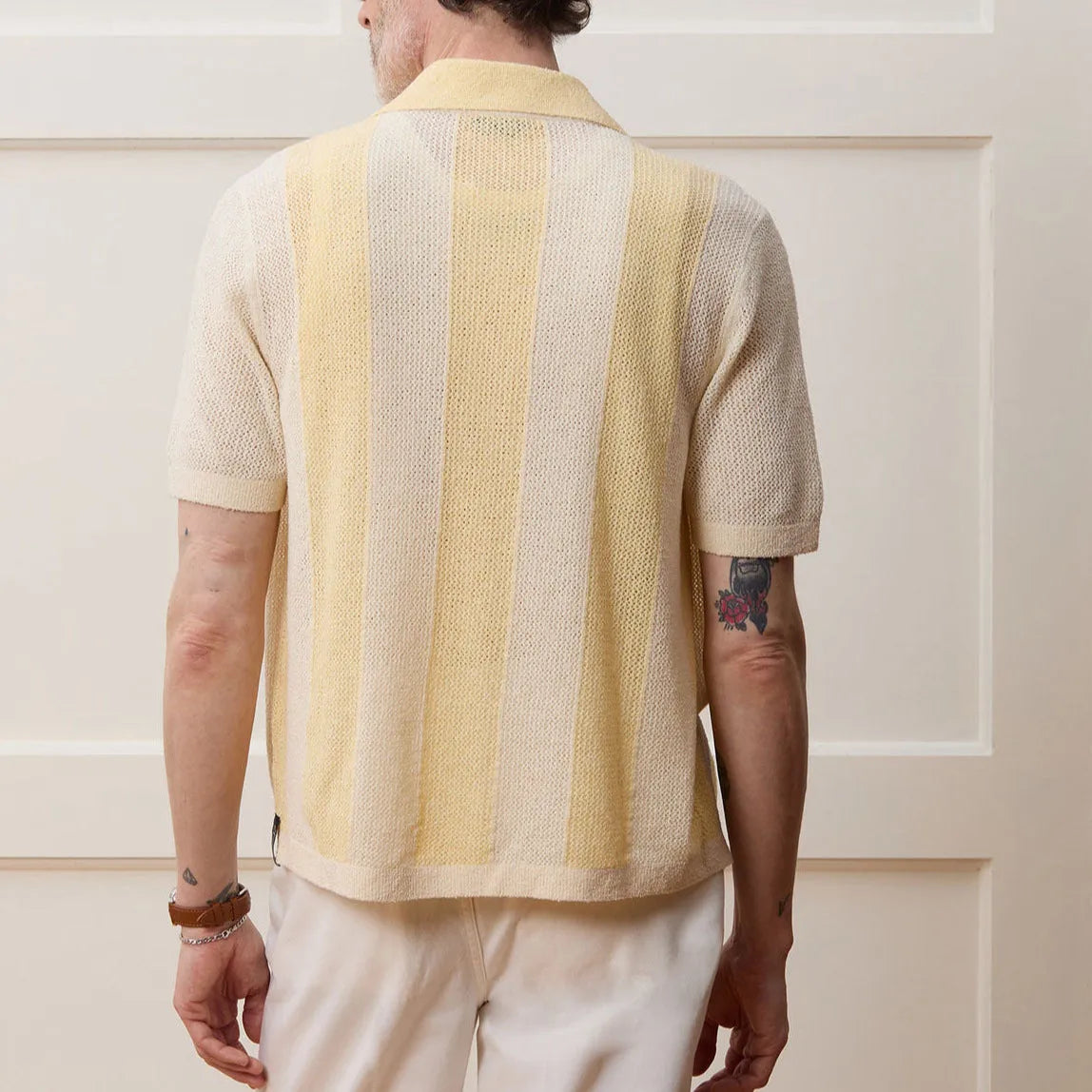 Yellow women's short-sleeved polo shirt with hollow-out asymmetric detail on a hanger.