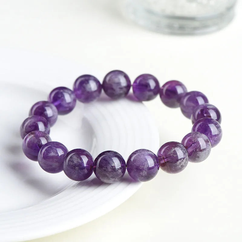 Natural purple feather amethyst crystal bracelet with scattered beads and geometric Ruyi pattern on a wrist.