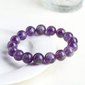 Natural purple feather amethyst crystal bracelet with scattered beads and geometric Ruyi pattern on a wrist.