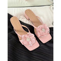 Women's chunky heel sandals with square toe, satin upper, and floral detail in cream-white.