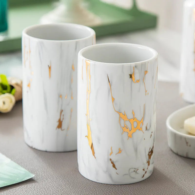 White marble ceramic bathroom wash kit with two cups, latex bottle, and soap box on a counter