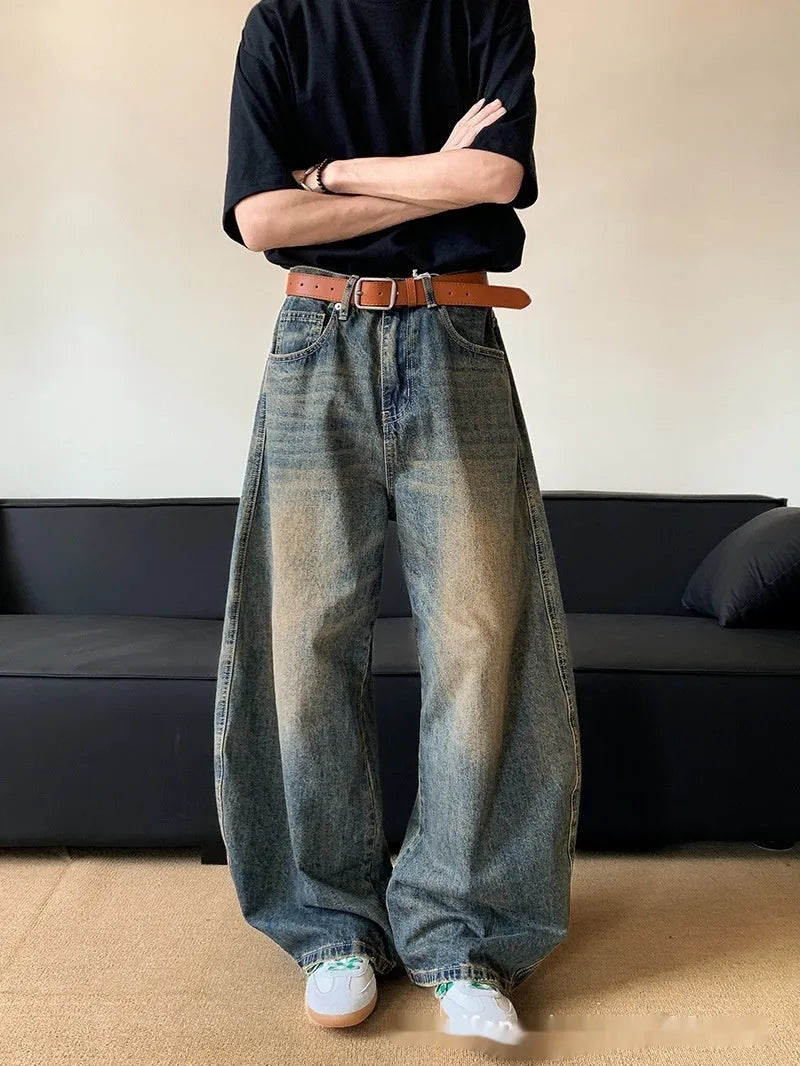 Man wearing retro blue distressed denim wide-leg trousers with a slim fit and zipper fly