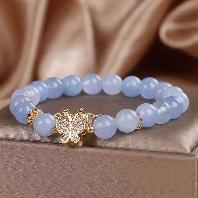 Sky blue crystal butterfly stretch bracelet for women with pearl and rhinestone accents on a plain background