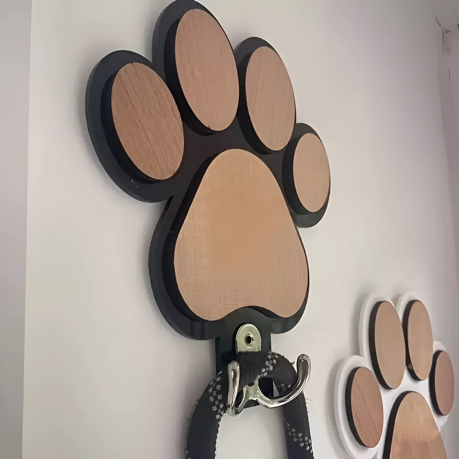 Wooden foot paw print hook in black colour on a white wall for household organisation