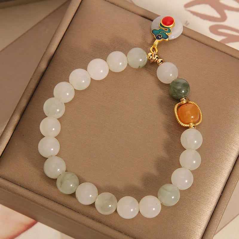Women's ice jade bracelet with pearl accents and a Xiangyun jade buckle on a wrist.