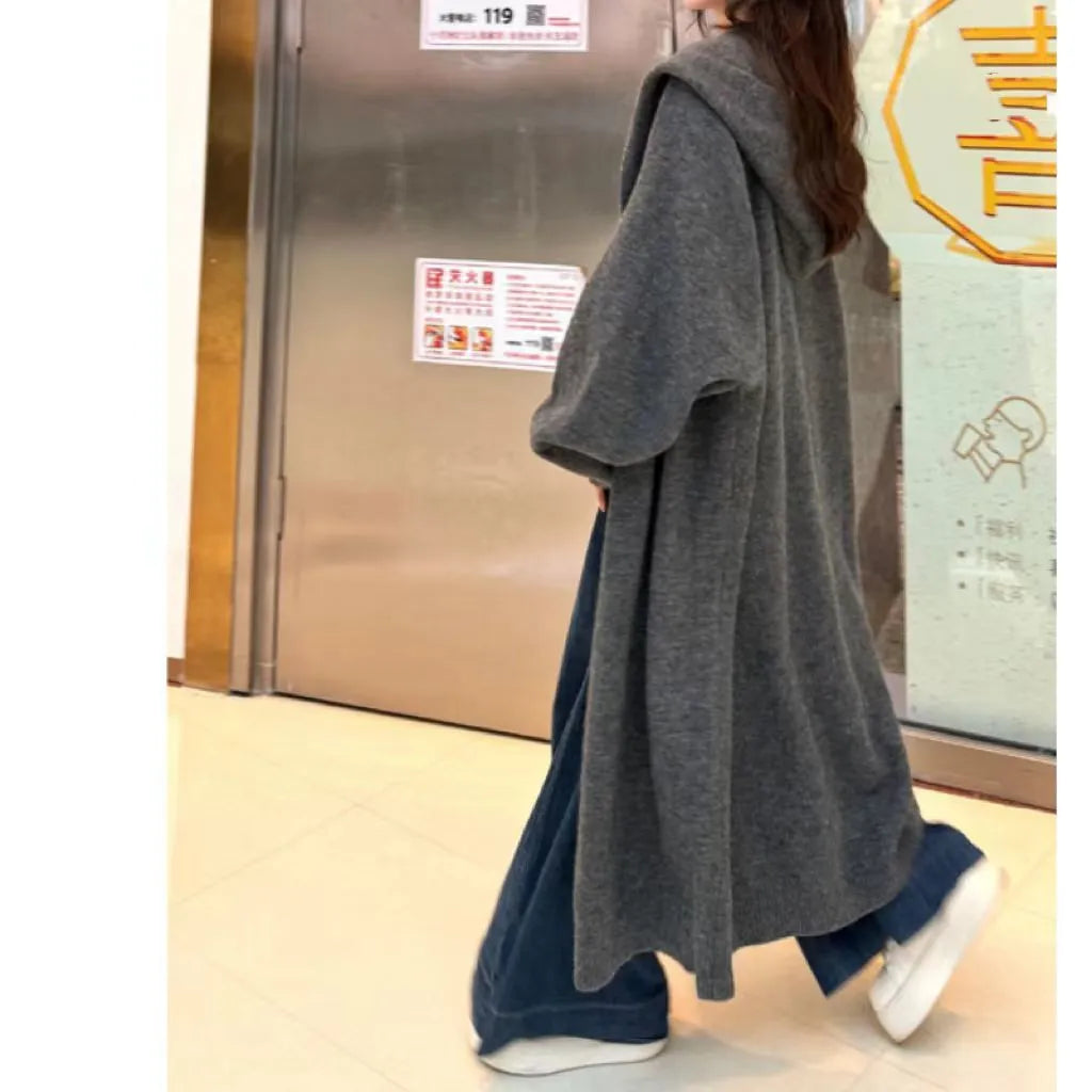 Woman wearing a long, loose, hooded knitted cardigan in a neutral colour, Korean casual style.