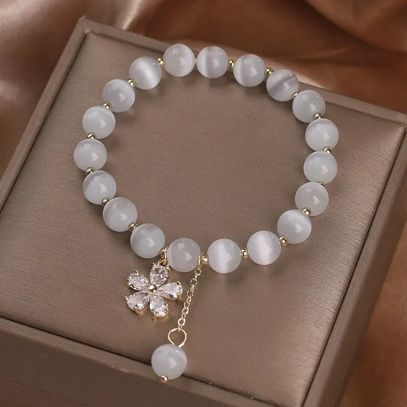 Women's white cat's eye stone bracelet with floral tassel and safety buckle clasp.