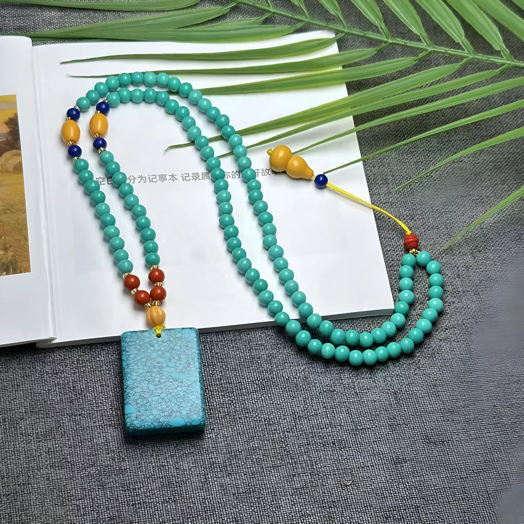 Turquoise stone lucky pendant necklace with hand-woven mesh flower design on a ball bead chain.