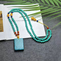 Turquoise stone lucky pendant necklace with hand-woven mesh flower design on a ball bead chain.
