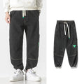 Men's loose-fit tapered cotton trousers in grey shown flat, with mid waist and tapered leg detail.
