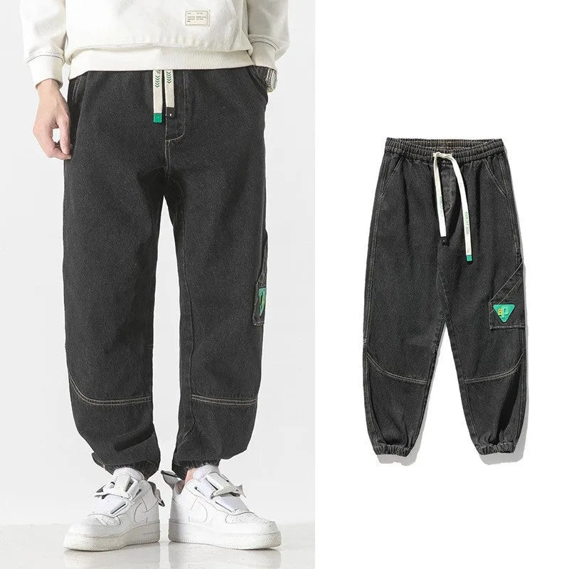 Men's loose-fit tapered cotton trousers in grey shown flat, with mid waist and tapered leg detail.