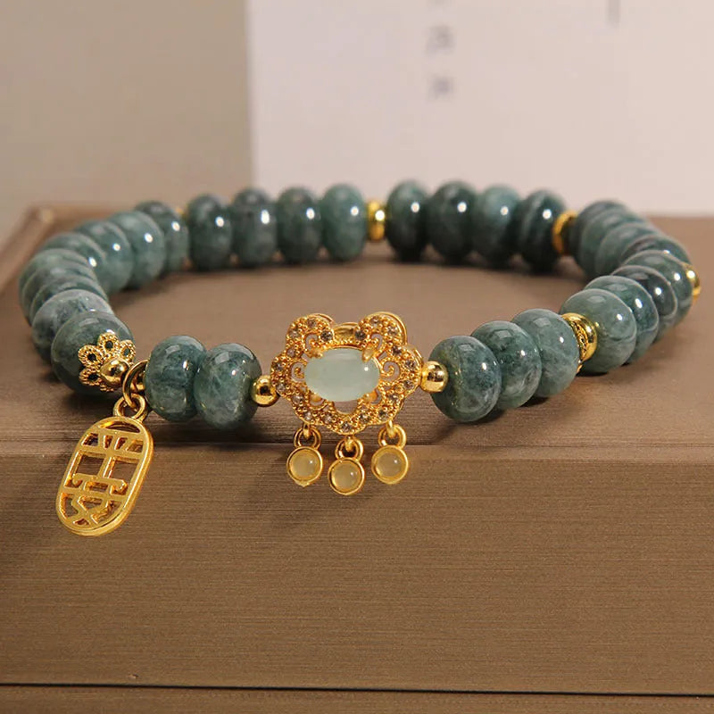 Close-up of a women's bracelet with green emerald jade abacus beads and a metallic alloy safety lock clasp.