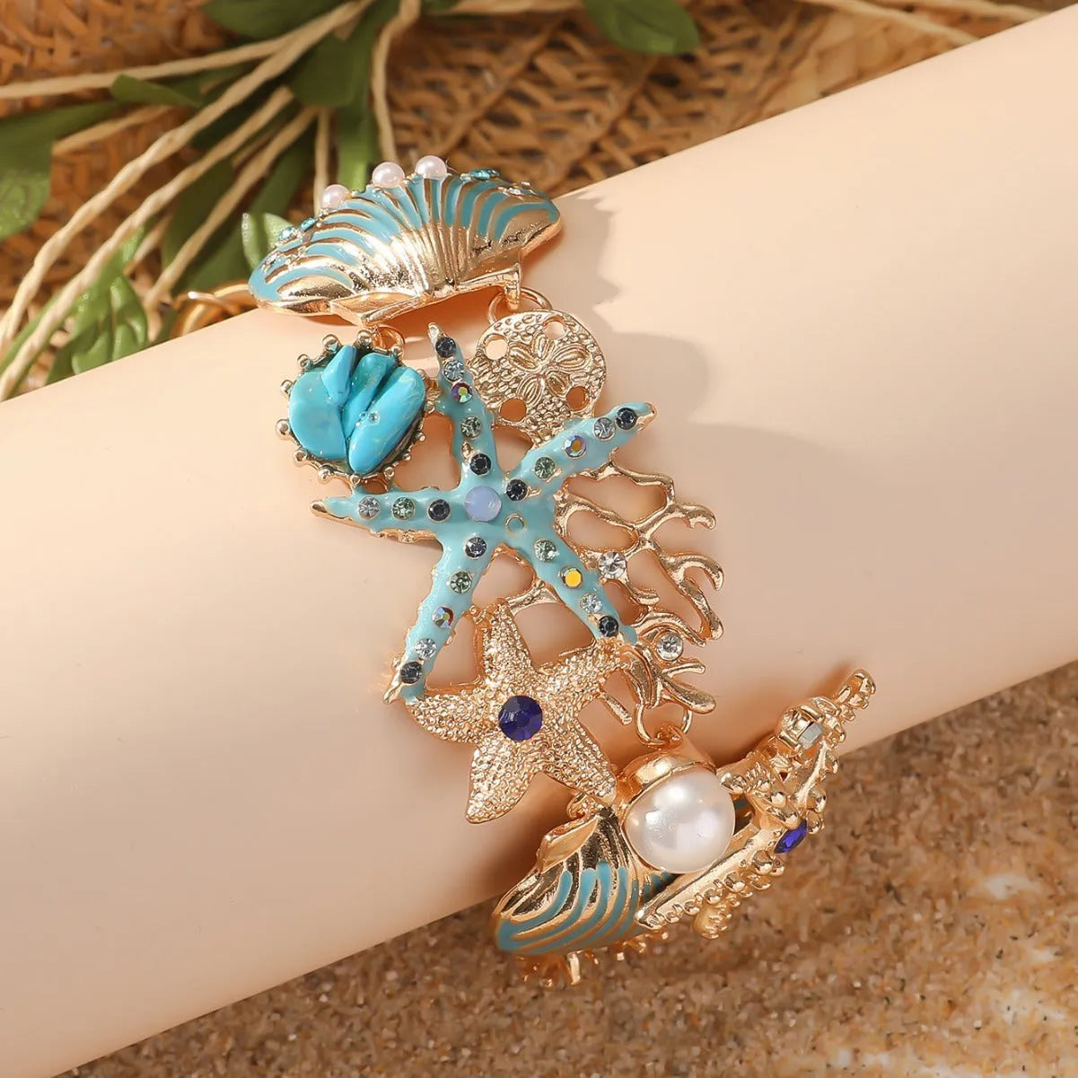 Alloy starfish bracelet with blue coral rhinestone boat anchor charm on a wrist.