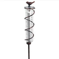 Hummingbird-shaped glass rain gauge on a cast iron base for garden precipitation measurement.