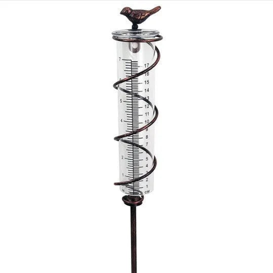 Hummingbird-shaped glass rain gauge on a cast iron base for garden precipitation measurement.